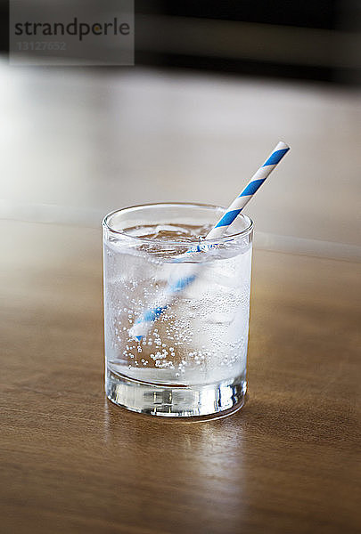 Nahaufnahme von kohlensäurehaltigem Wasser in Glas auf einem Holztisch zu Hause