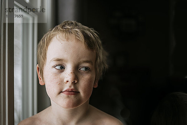 Nahaufnahme eines Jungen  der in der Dunkelkammer durch den Seitenblick blickt