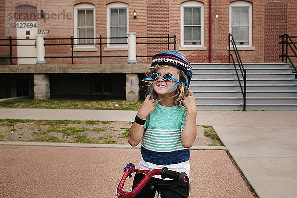 Glückliches Mädchen mit Schutzbrille beim Stehen mit Fahrrad