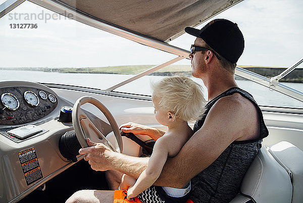 Seitenansicht eines Vaters mit Sohn am Steuer eines Motorbootes