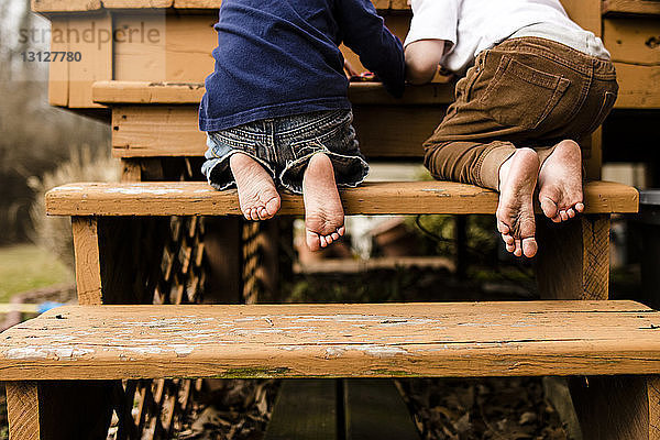 Niedrige Sektion von Brüdern  die auf Stufen auf dem Spielplatz kniend spielen