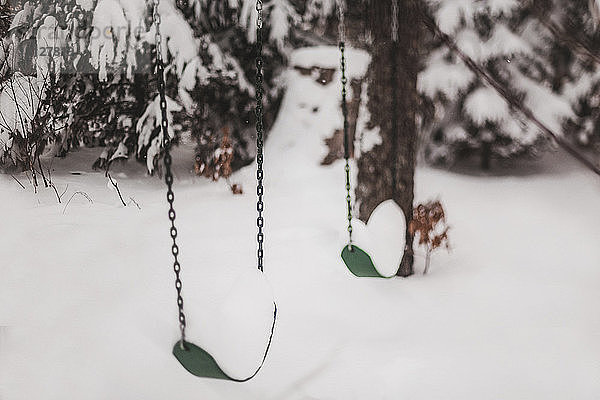 Schaukeln hängen im Winter über schneebedecktem Feld am Spielplatz