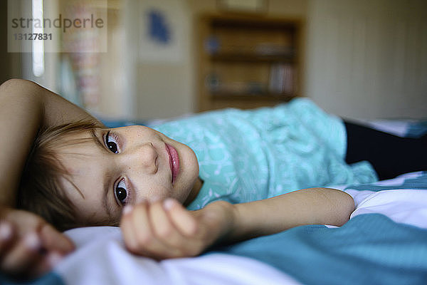 Porträt eines selbstbewussten Mädchens auf dem Bett liegend