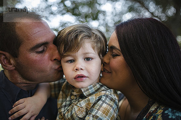 Porträt eines süßen Sohnes mit sich auf dem Feld küssenden Eltern