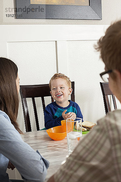 Eltern sitzen mit dem Jungen beim Frühstück zu Hause