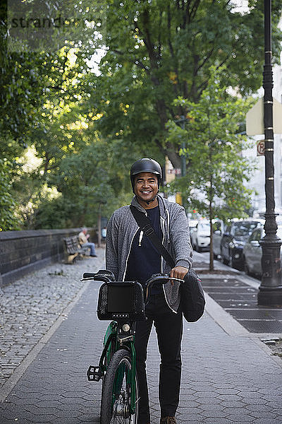Porträt eines glücklichen Mannes mit Fahrrad auf einem Fußweg in der Stadt