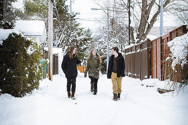 Glückliche Geschwister laufen auf schneebedecktem Fußweg