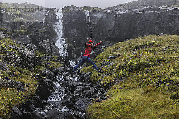 Seitenansicht eines Wanderers  der gegen einen Wasserfall springt