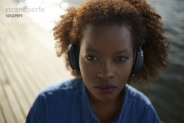 Porträt einer selbstbewussten Frau  die Musik hört  während sie auf einem Fußweg steht