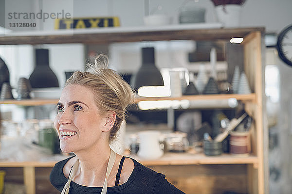 Lächelnde Frau schaut auf  während sie im Workshop steht