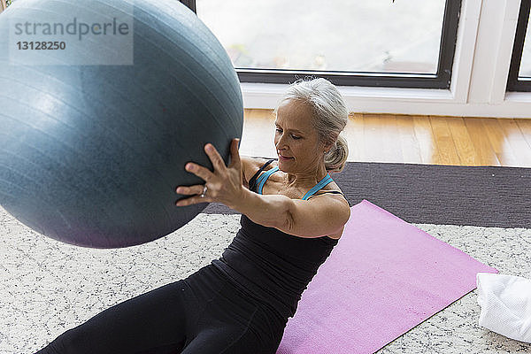 Ältere Frau hält Fitnessball beim Heimtraining