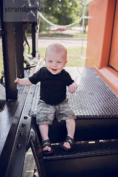 Süßer kleiner Junge sitzt auf einem Spielgerät auf dem Spielplatz