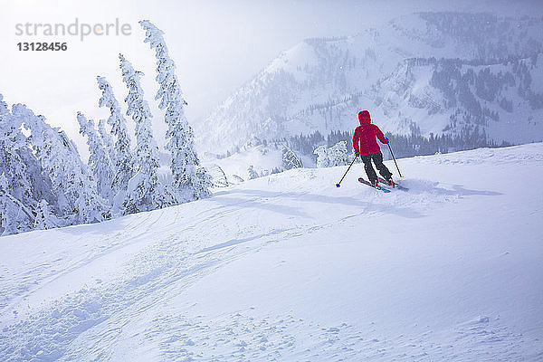 Rückansicht einer Frau beim Skifahren in schneebedeckter Landschaft