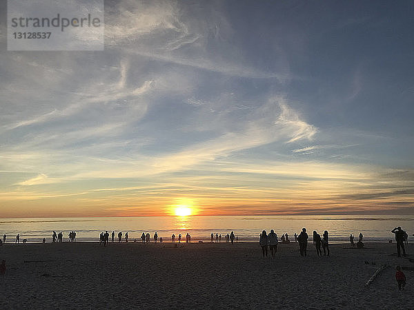Silhouette der Menschen am Strand gegen den Himmel bei Sonnenuntergang
