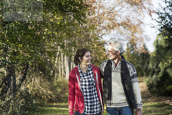 Mann und Enkelin unterhalten sich beim Spaziergang auf dem Feld inmitten von Bäumen