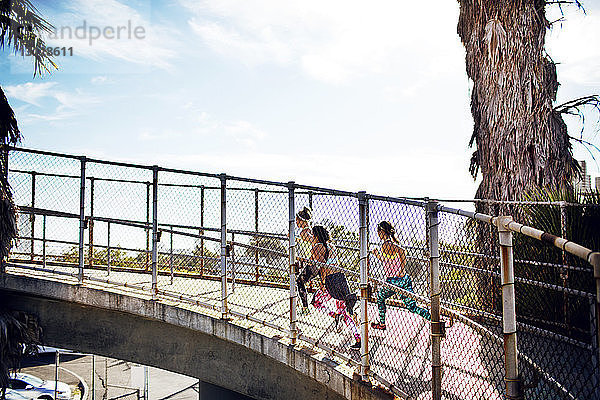 Seitenansicht von Joggerinnen auf der Brücke gegen den Himmel