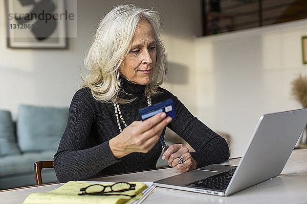 Ältere Frau benutzt Laptop-Computer beim Bezahlen von Rechnungen zu Hause