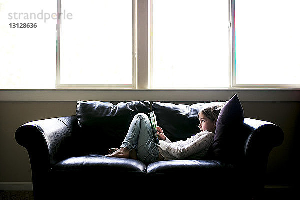 Seitenansicht eines zu Hause auf dem Sofa liegenden Mädchens