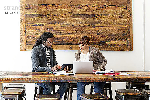 Kreative Geschäftskollegen nutzen Laptop-Computer  während sie im Büro am Konferenztisch sitzen