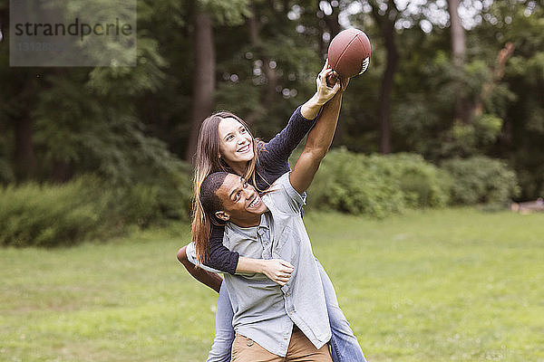 Mann nimmt Frau beim Fussballspielen auf dem Feld huckepack