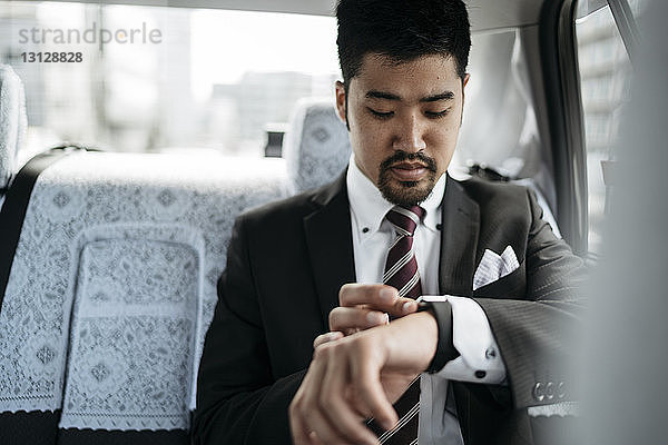 Geschäftsmann überprüft die Zeit auf einer intelligenten Uhr  während er im Taxi sitzt