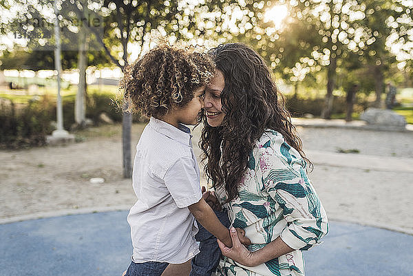 Lächelnde Mutter spielt mit Sohn im Park