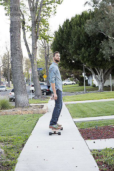 Porträt eines Mannes beim Skateboarden auf einem Fußweg
