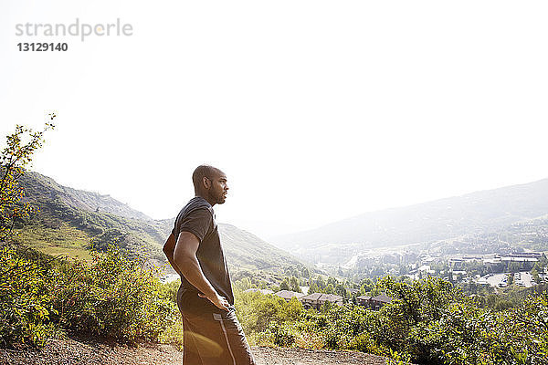 Seitenansicht eines Mannes  der die Landschaft betrachtet  während er auf einem Berg vor klarem Himmel steht