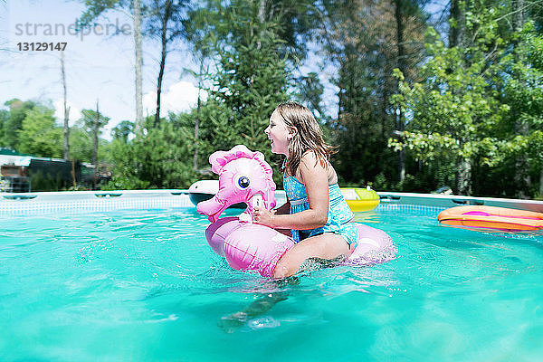 Seitenansicht eines glücklichen Mädchens mit aufblasbarem Ring beim Spielen im Schwimmbad