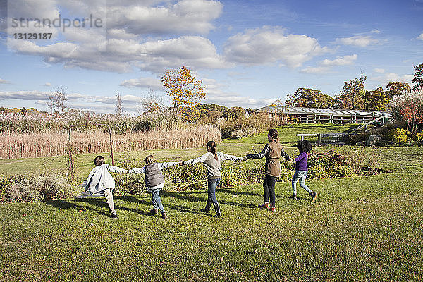Lehrer spielt während der Exkursion mit den Schülern auf einem Grasfeld