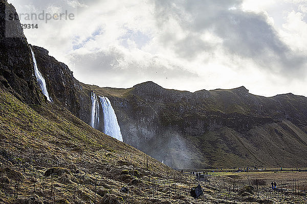 Blick auf den Seljalandsfoss-Wasserfall und die Berge vor bewölktem Himmel