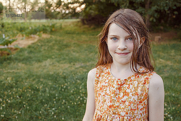 Porträt eines lächelnden Mädchens  das auf einem Grasfeld auf einem Bauernhof steht
