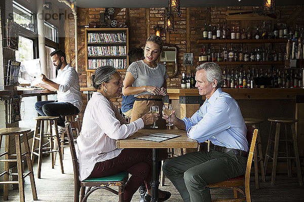 Kellnerin im Gespräch mit Kunden  die im Café sitzen