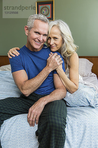 Porträt eines selbstbewussten Paares  das zu Hause auf dem Bett sitzt