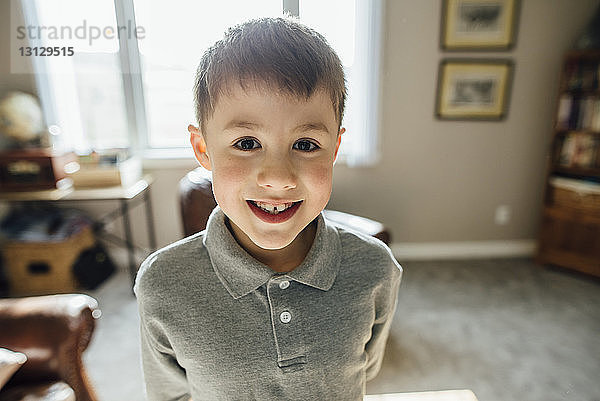 Porträt eines lächelnden Jungen  der zu Hause am Fenster steht