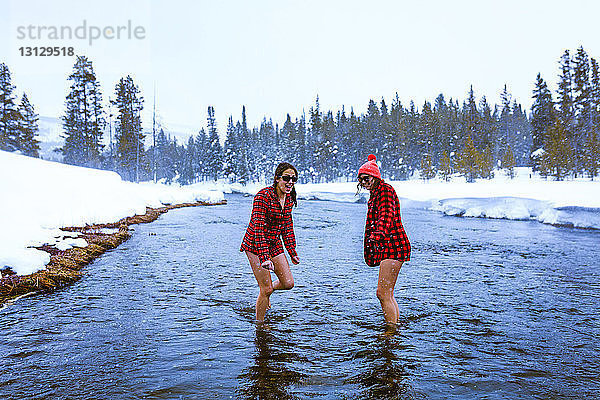 Freundinnen  die sich im Winter im See gegen den Himmel vergnügen