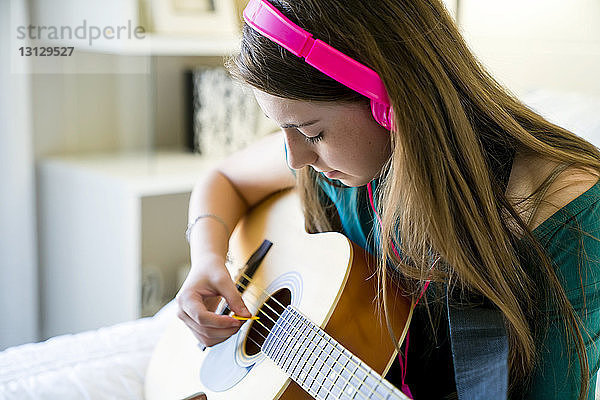 Teenager-Mädchen spielt Gitarre im Schlafzimmer