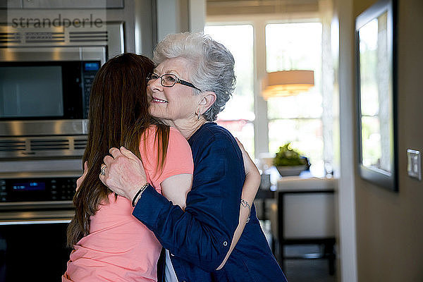 Glückliche Großmutter umarmt Enkelin zu Hause