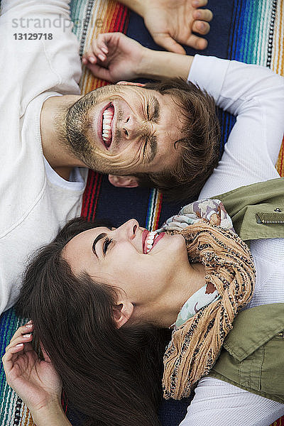 Hochwinkelaufnahme eines fröhlichen Paares  das im Park auf einer Decke liegt
