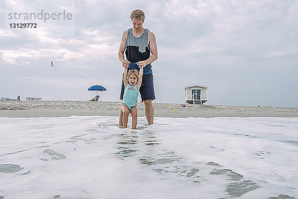 Vater und Tochter spielen in Wellen am Cape May Beach gegen den Himmel
