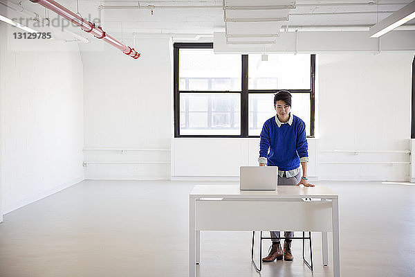 Porträt einer Geschäftsfrau mit Laptop-Computer am Stehtisch im neuen Büro