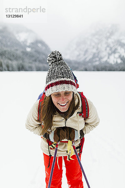 Lächelnde Frau wandert auf schneebedecktem Feld