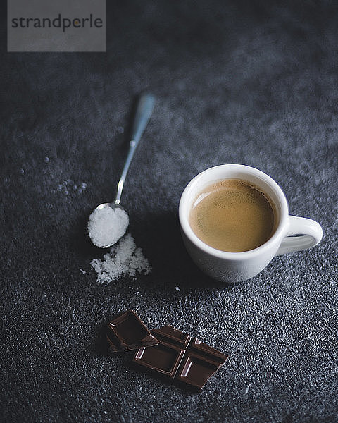 Schokoriegel mit Kaffeetasse und Zucker auf schwarzem Tisch