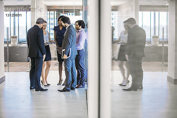 Geschäftsleute diskutieren im Stehen im Bürokorridor