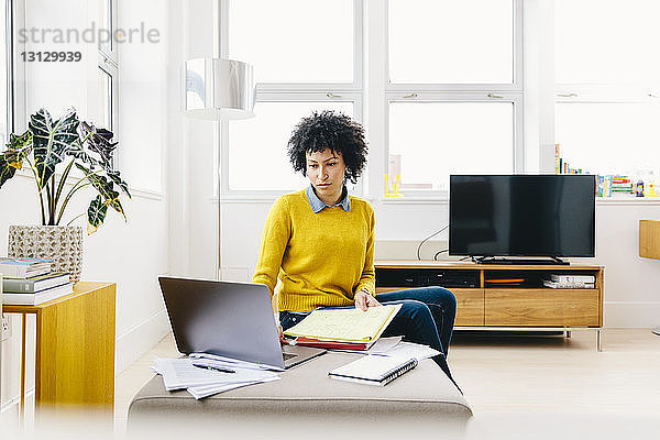 Seriöse Geschäftsfrau benutzt Laptop-Computer  während sie im Büro sitzt