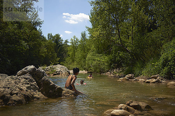 Mutter betrachtet Töchter  die im Fluss im Wald schwimmen