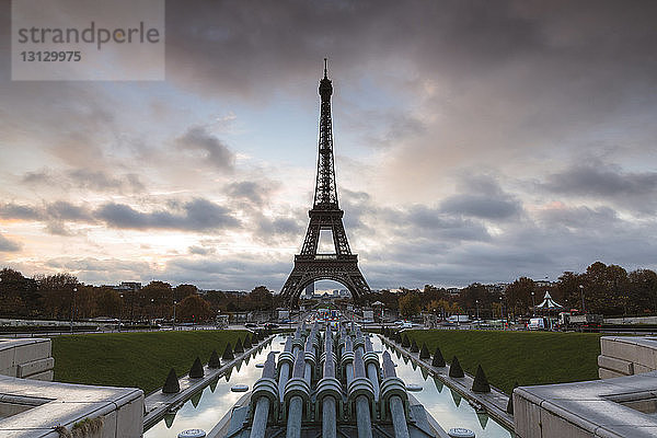 Eiffelturm und Trocadero-Brunnen gegen bewölkten Himmel bei Sonnenuntergang