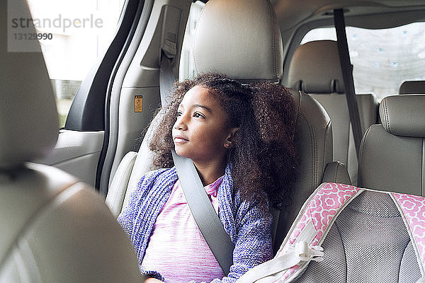 Nachdenkliches Mädchen schaut durchs Fenster  während sie im Auto unterwegs ist