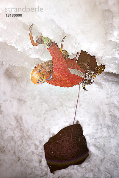 Hochwinkelaufnahme eines Wanderers  der einen gefrorenen Wasserfall besteigt