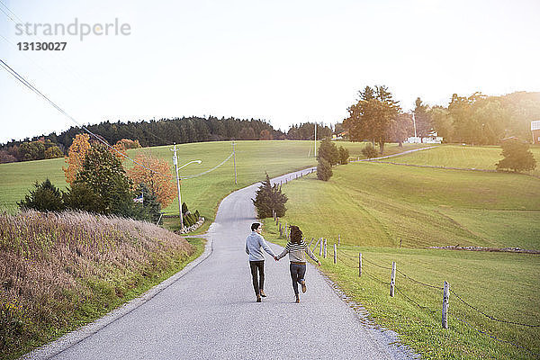 Spielerisches Paar rennt auf dem Fußweg gegen den Himmel